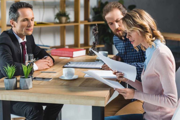 side view of concentrated couple reading contract during meeting with lawyer in office