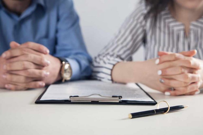 Couple with divorce contract and ring on desk. Divorce