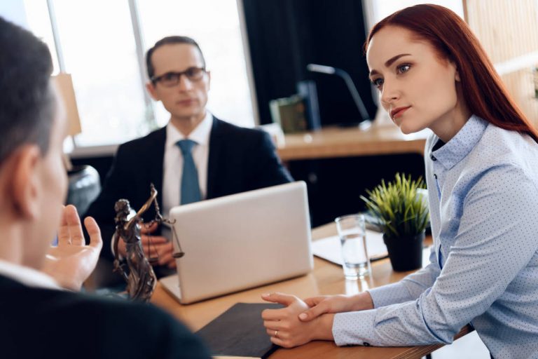 woman listens attentively to man looking at divorce attorney. Attorney in business suit is sitting at office table, listening to discussion of divorcing couple.