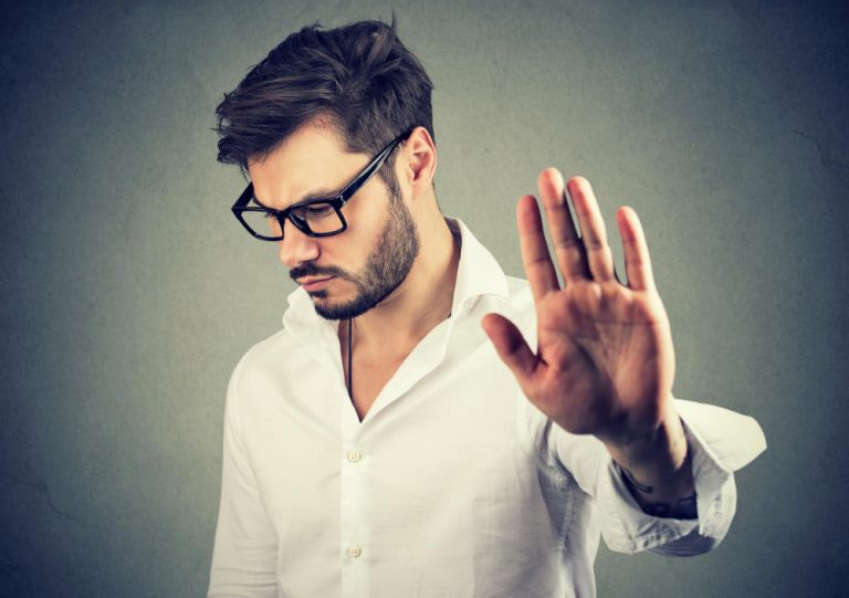 Annoyed sad man giving talk to hand gesture isolated on gray background. Negative emotion face expression feeling body language