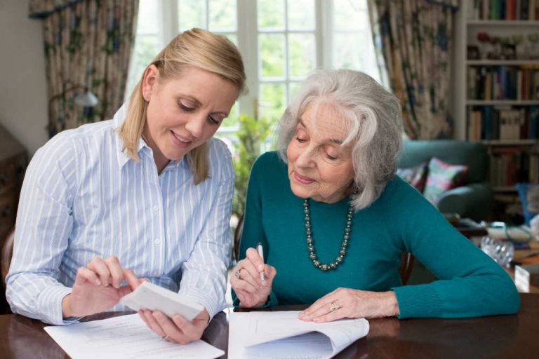 Woman Helping Senior Neighbor With Paperwork