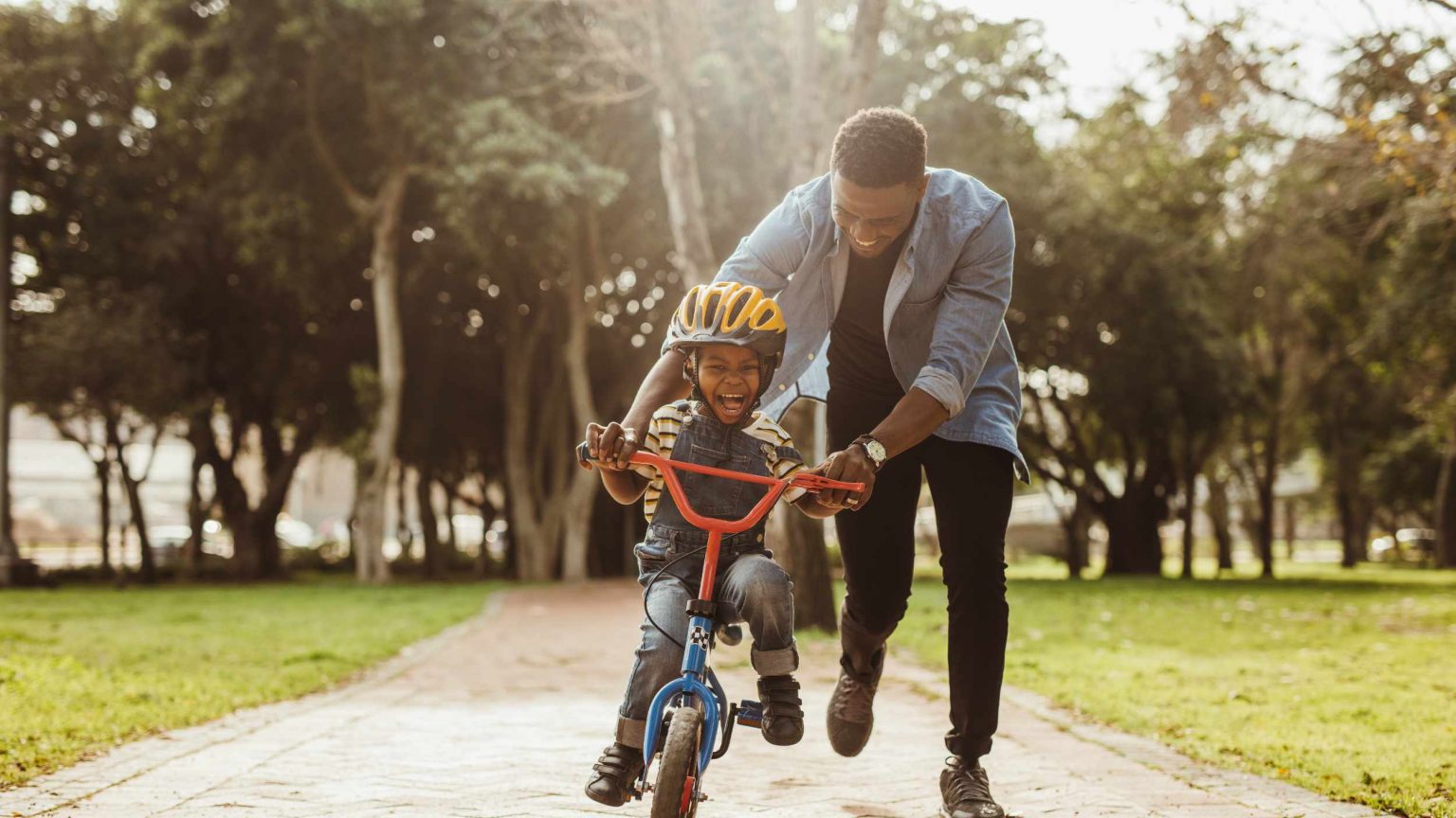 Father teaching his son cycling at park