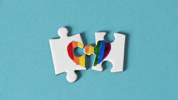two pieces of a puzzle, which put together form a rainbow heart, on a blue background, depicting the lack of right of same-sex marriage or the divorce of same-sex couples