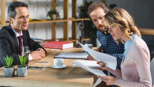 side view of concentrated couple reading contract during meeting with lawyer in office