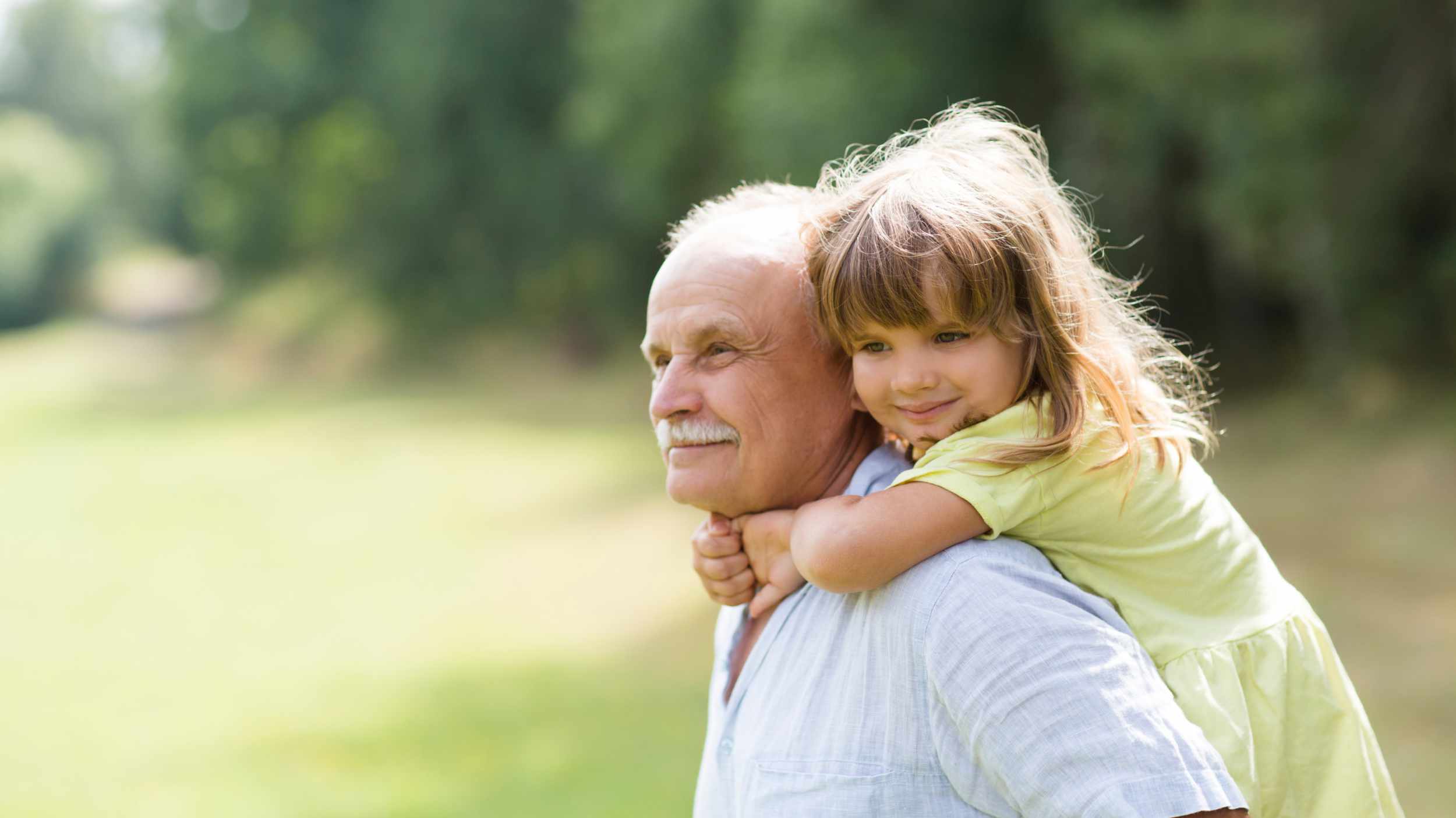 Little child girl hugs grandpa On Walk in the summer outdoors. Concept of friendly family.
