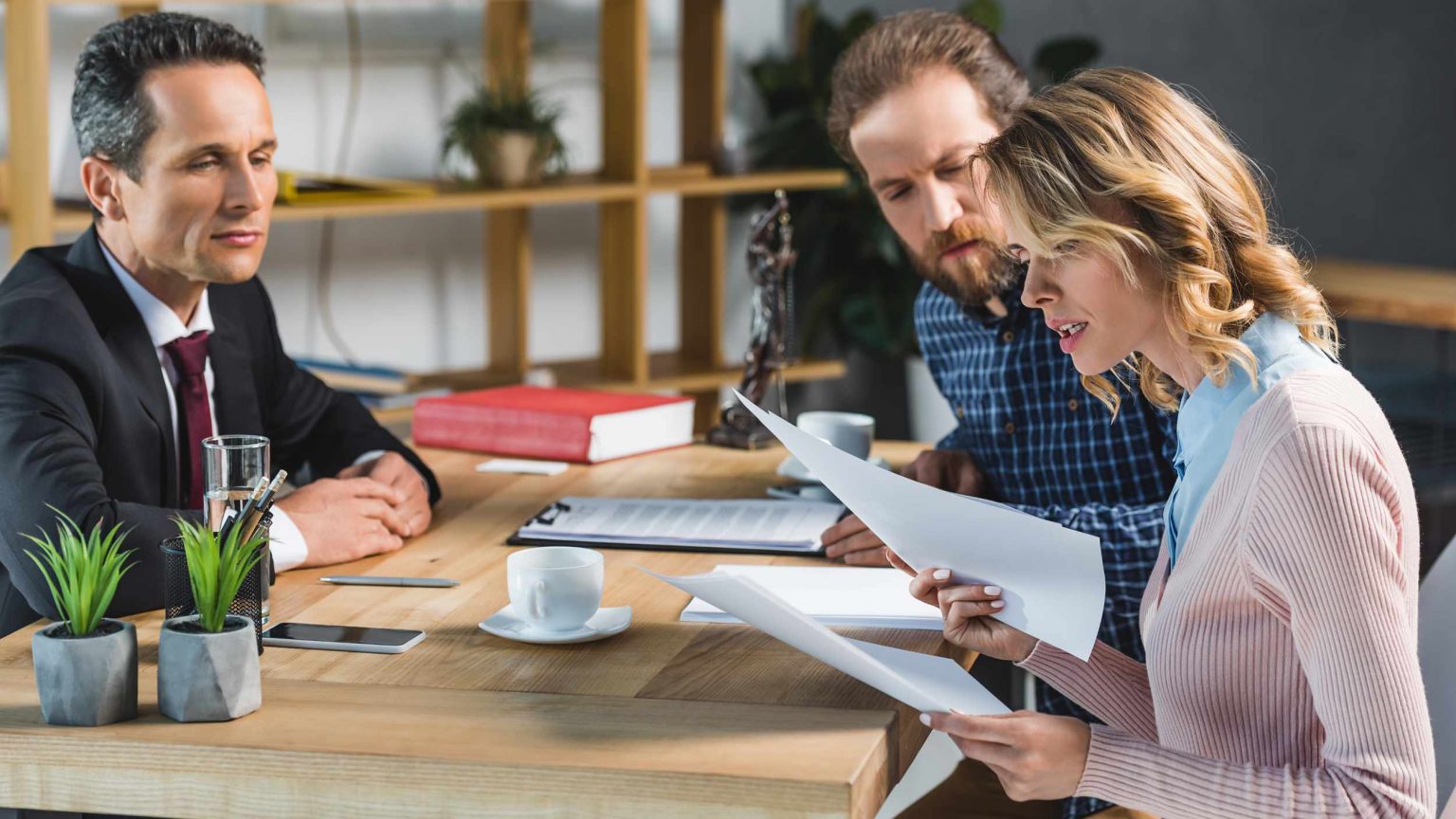 side view of concentrated couple reading contract during meeting with lawyer in office