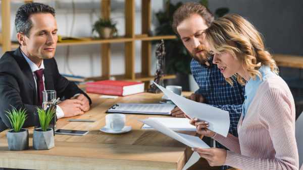 side view of concentrated couple reading contract during meeting with lawyer in office