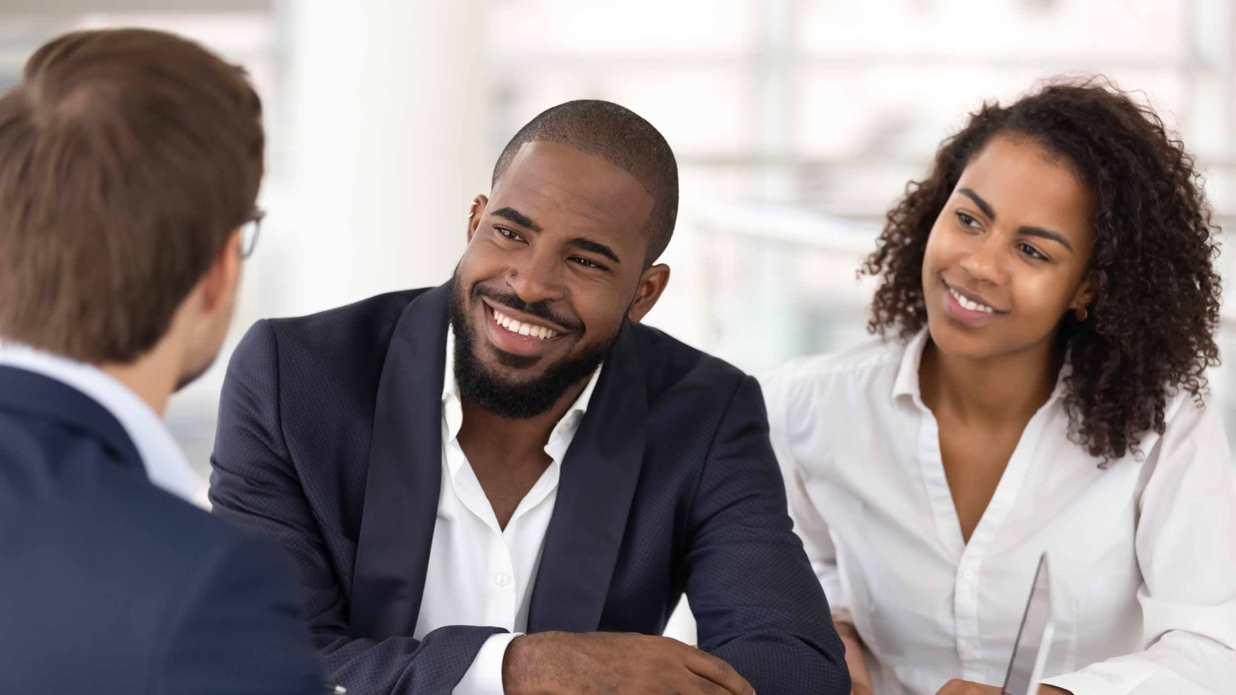 Happy african american young family couple listen to realtor insurer salesman consulting black clients at meeting, bank manager agent talking to customers explaining insurance loan mortgage deal