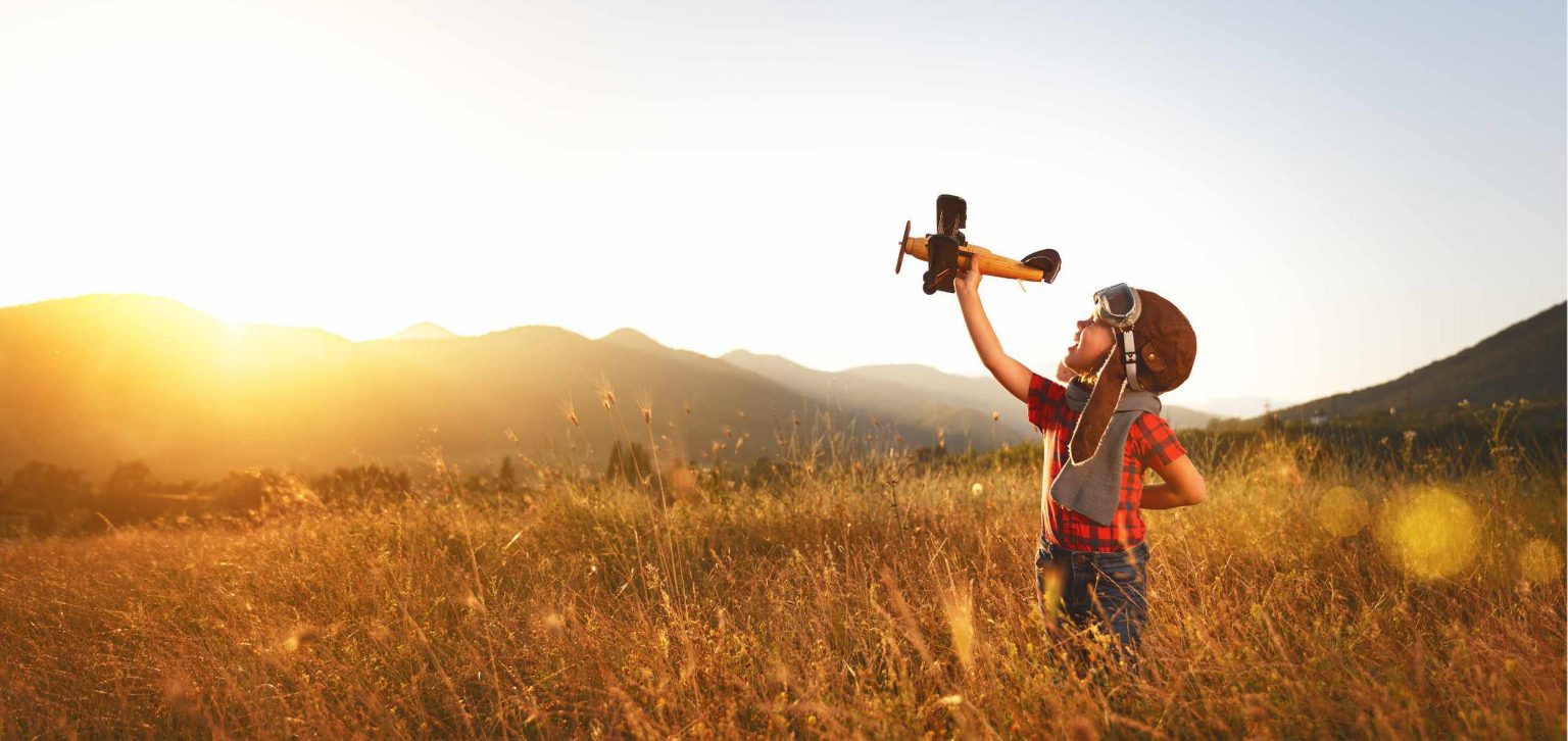 Child playing with airplane in field