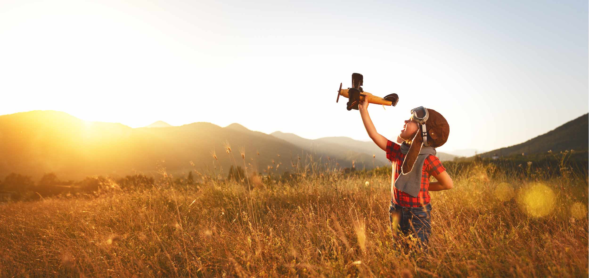 Child pilot aviator with airplane dreams of traveling in summer in nature at sunset