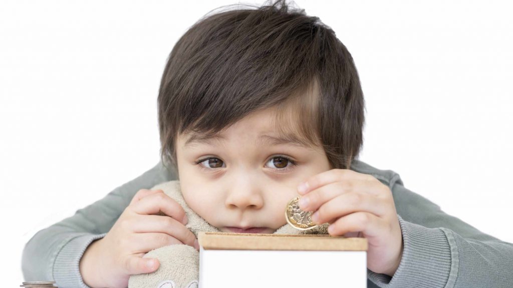 Selective focus kid boy putting pound coin on a moneybox isolated on white background, Adorable boy counting his saved coins and looking at cameara, Child learning about saving concept