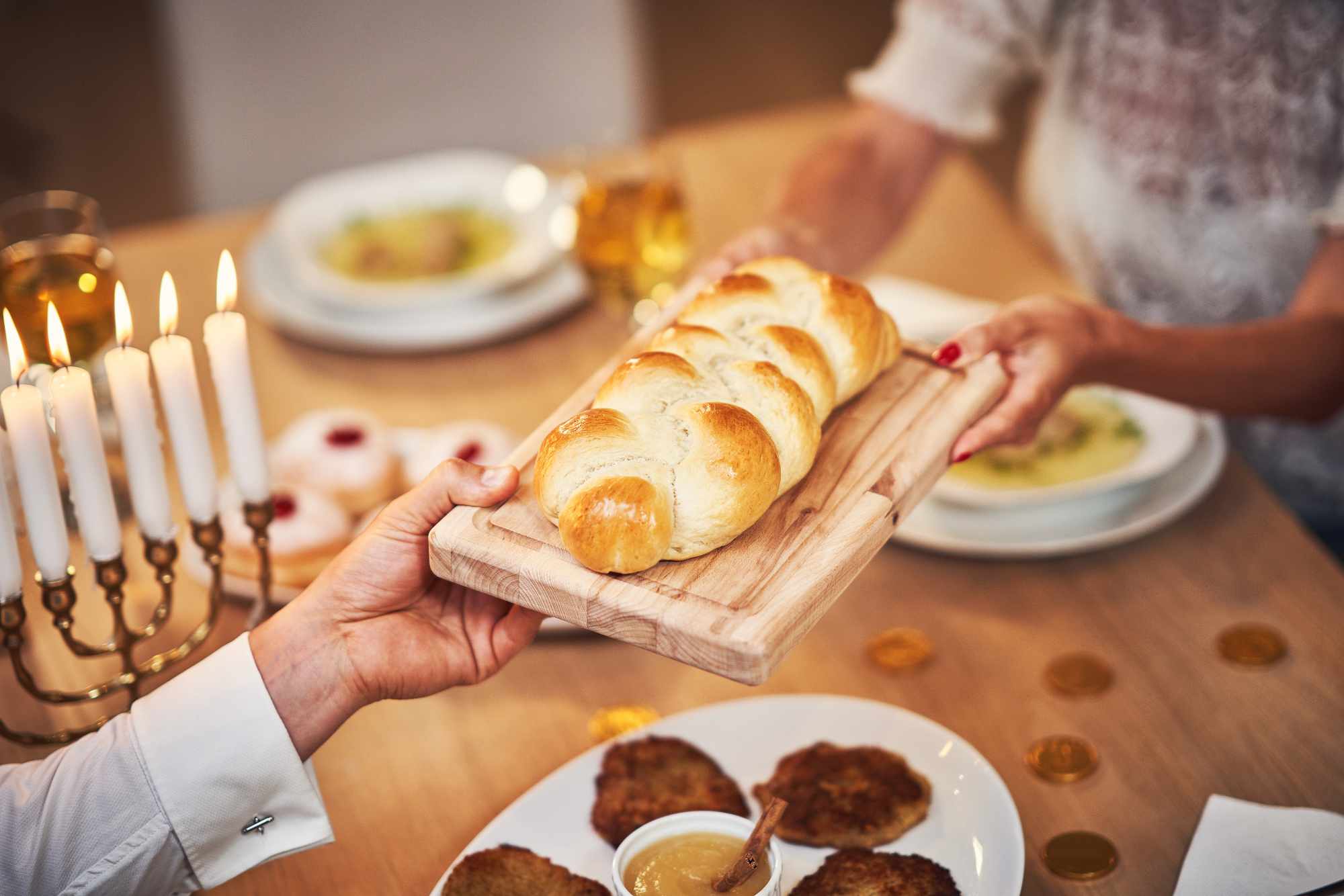 Picture of Hanukkah dinner. Family gathered around the table with traditional dishes